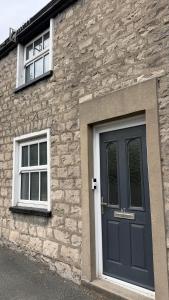 a stone house with a blue door and two windows at The Burrow in Kendal
