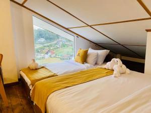 two beds in a room with a large window at Infinity Winter Resort in Nuwara Eliya