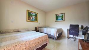 a bedroom with two beds and a desk and a chair at Pássaros do Cerrado Suítes in Alto Paraíso de Goiás