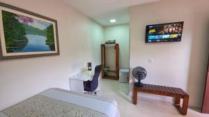 a room with a bed and a desk and a tv at Pássaros do Cerrado Suítes in Alto Paraíso de Goiás