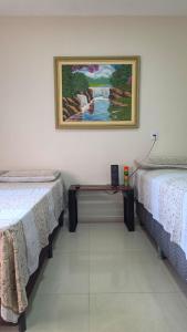 a room with two beds and a painting on the wall at Pássaros do Cerrado Suítes in Alto Paraíso de Goiás