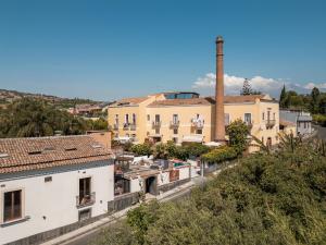 a view of a building with a factory in the background at Capomulini Boutique Hotel in Capo Mulini