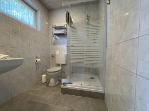 a bathroom with a shower and a toilet and a sink at Pension Murra in Stedesdorf