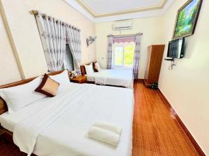a bedroom with two beds and a tv and a window at Hoa Phuong Hotel Phong Nha in Phong Nha