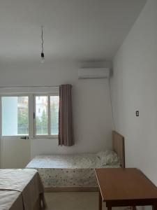 a room with two beds and a window and a table at Infinity room in Velipojë
