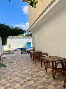 a patio with wooden tables and benches next to a building at Renascer Suites in Búzios