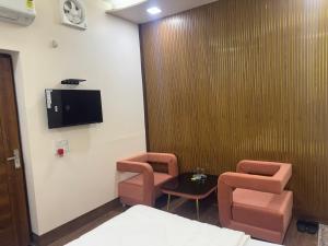 a room with two chairs and a tv on the wall at Hotel American in Sahāranpur +13 photos