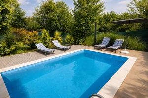 a blue swimming pool with chairs and an umbrella at Casa Bella Fruška Gora with HOT TUB in Velika Remeta