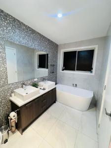 a bathroom with two sinks and a tub and a mirror at Mickleham Prestige Homestay in Mickleham