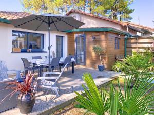 a patio with a table and chairs and an umbrella at Maison proche plage et Golf in Moliets-et-Maa