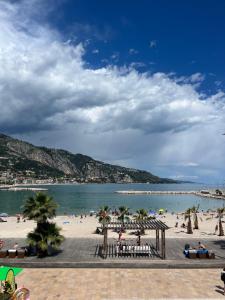 a beach with palm trees and people on the beach at Monaco - Menton Old Town - Climatisation - Seaview - Luxury rénovation in Menton