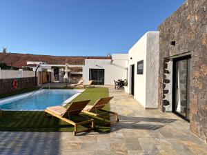 a backyard with a swimming pool and two lounge chairs at Casa El Cachorro in La Oliva