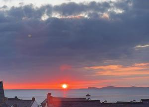a person standing on top of a building watching the sunset at Sunset Bed and Breakfast in Broad Haven