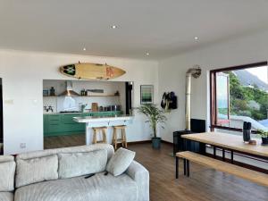 a living room with a couch and a table with a surfboard at The Lookout - Spacious 2 bed overlooking Kalk Bay in Kalk Bay