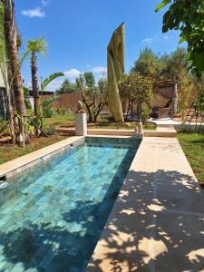 a swimming pool in a yard with a tree at La villa de mamie in Dar Ito Lahssene