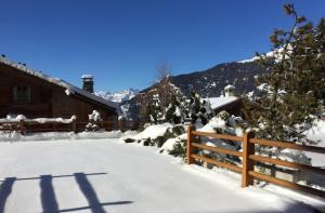 um quintal coberto de neve com uma cerca e uma casa em Verbier Medran apartment em Verbier