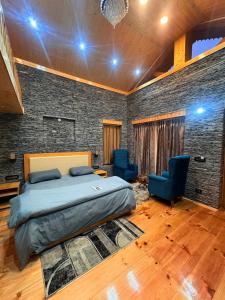 a bedroom with a bed and two blue chairs at The Pravaas Resort in Barot 