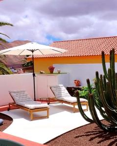 a patio with two chairs and an umbrella and cactus at Casa Yahshua in Villaverde