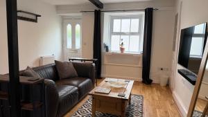 a living room with a leather couch and a coffee table at The Burrow in Kendal