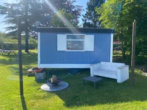 a blue tiny house with a bench in the grass at Sky Ballonvaarten & Accommodaties in Tilburg