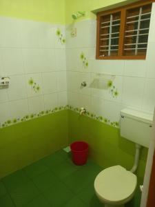 a green and white bathroom with a toilet and a window at AS Villa Homestay in Varkala