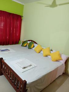 a large bed with yellow pillows and a red curtain at AS Villa Homestay in Varkala