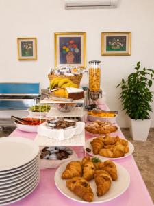 a table with plates of food on a pink table at Hotel Le Ali in Rimini