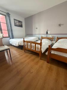 a bedroom with two beds and a wooden floor at Hôtel du Commerce - Centre Millau in Millau