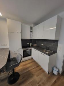 a kitchen with white cabinets and a desk and a chair at Apartment Karin in Langenwang +7 photos