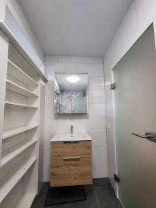 a bathroom with a sink and a mirror and shelves at Apartment Karin in Langenwang