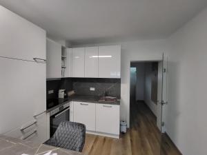 a kitchen with white cabinets and a chair in a room at Apartment Karin in Langenwang