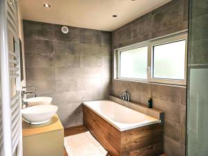 a bathroom with a tub and a toilet and a sink at Modern Spacious Forest Home in Aywaille +21 photos