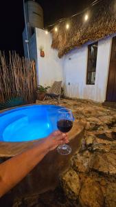 a person holding a glass of wine next to a hot tub at Cabañas Los Gallitos Ecolodge 3 in Sacalum