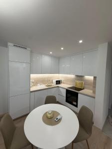 a white kitchen with a white table and chairs at Meddy Luxury Apartment in Mostar +11 photos