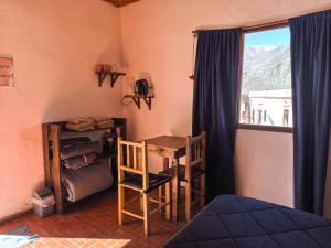 a room with a bed and a table and a window at ElPoro in Purmamarca