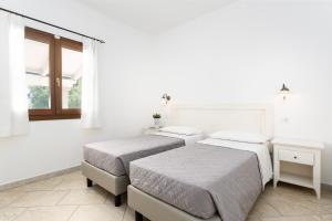 two beds in a room with white walls at Residence con piscina Piricone in Orosei +54 photos