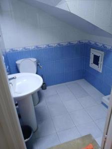 a blue tiled bathroom with a toilet and a sink at Appartement Détente Hammamet in Hammamet
