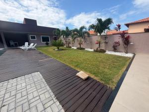 a backyard with a wooden deck and a lawn at Faith Home 1 in Arraial do Cabo