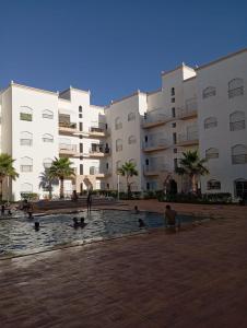a group of people in a pool in front of a building at Appartement avec piscine, résidence assadaka in Saïdia