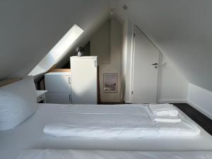 a white bedroom with a bed and a refrigerator at Ferienwohnung Coasty - Timmendorfer Strand in Timmendorfer Strand