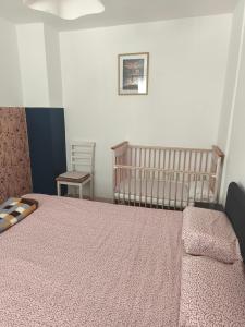 ein Schlafzimmer mit einem Bett, einem Kinderbett und einem Stuhl in der Unterkunft Ki-Mi-Self Check-In in Krapina