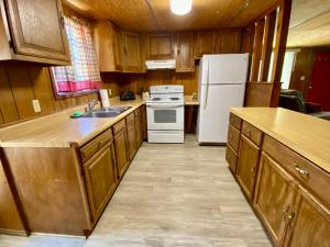 a kitchen with wooden cabinets and a white refrigerator at Shady Oak in Concan +18 photos