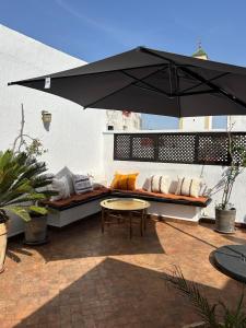 a patio with a table and a bench with an umbrella at Riad Dar Lina Logement entier in Rabat