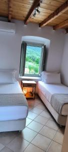 two beds in a room with a window at Vrisi House in Kiparission