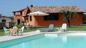 a pool with chairs and an umbrella next to a house at B&B La Camilla in Sipicciano