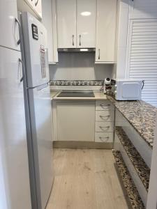a kitchen with white cabinets and a refrigerator at Carihuela Beach in Torremolinos