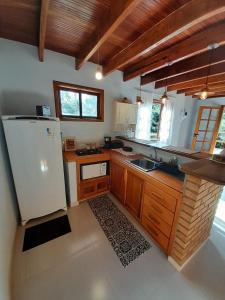 a kitchen with a white refrigerator and a sink at Chalé Terra Nova in Itamonte