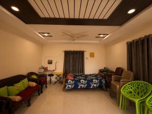 a living room with a bed and chairs and a ceiling at Hotel Moturi Farmstay Vemulawada in Vemalwāda