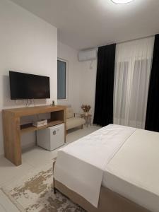 a bedroom with a bed and a flat screen tv at Villa Thalassa Lal'Andrea in Dhërmi