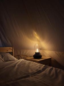 a candle on a night stand next to a bed at Pajtl indoor glamping in Črna na Koroškem +8 photos